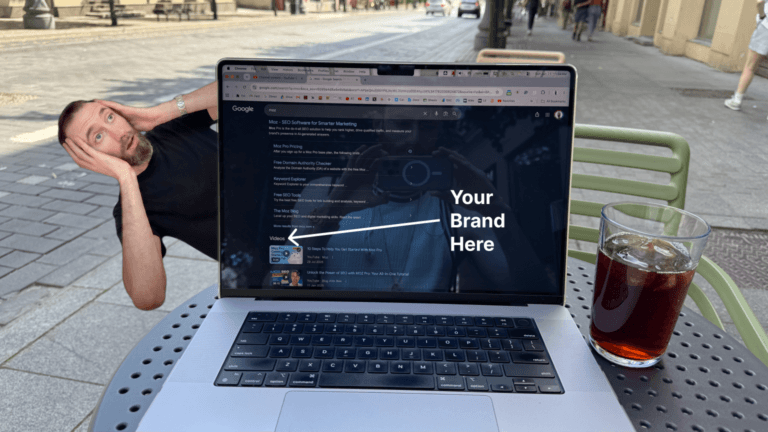 Laptop on an outdoor cafe table showing a Google search for “moz,” with video results under the brand’s homepage and a white arrow labeled “Your Brand Here,” illustrating how competitor brand searches can surface YouTube videos before buyers choose another company.