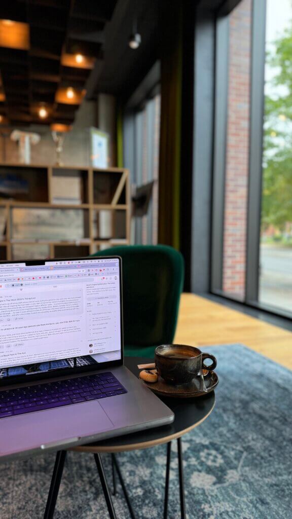 Inside Wrocław's Bridge Hotel: A laptop next to an americano with a cookie.