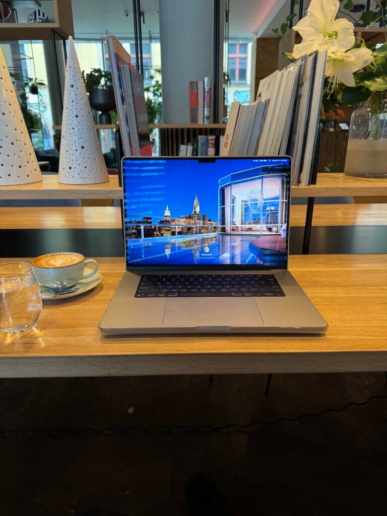 Edward Sturm's laptop in a PURO Hotel café with a perfect cappuccino next to it.