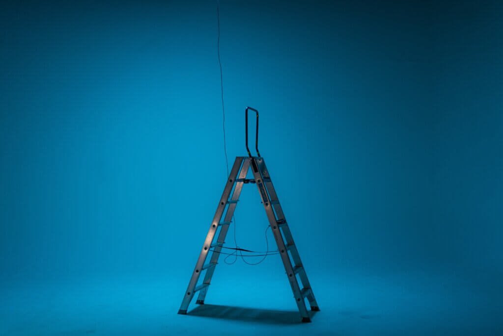 A metal ladder against a blue backdrop