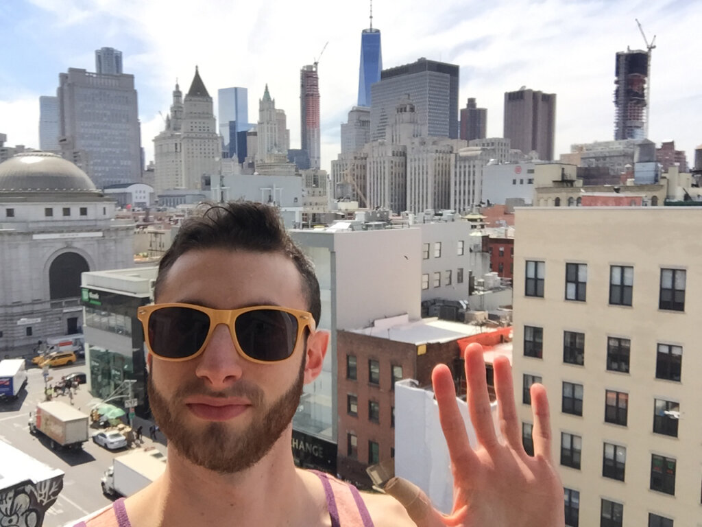 Edward Sturm in yellow sunglasses on a terrace in Chinatown, NYC. The World Trade Center is in the background. Photo taken 2015.