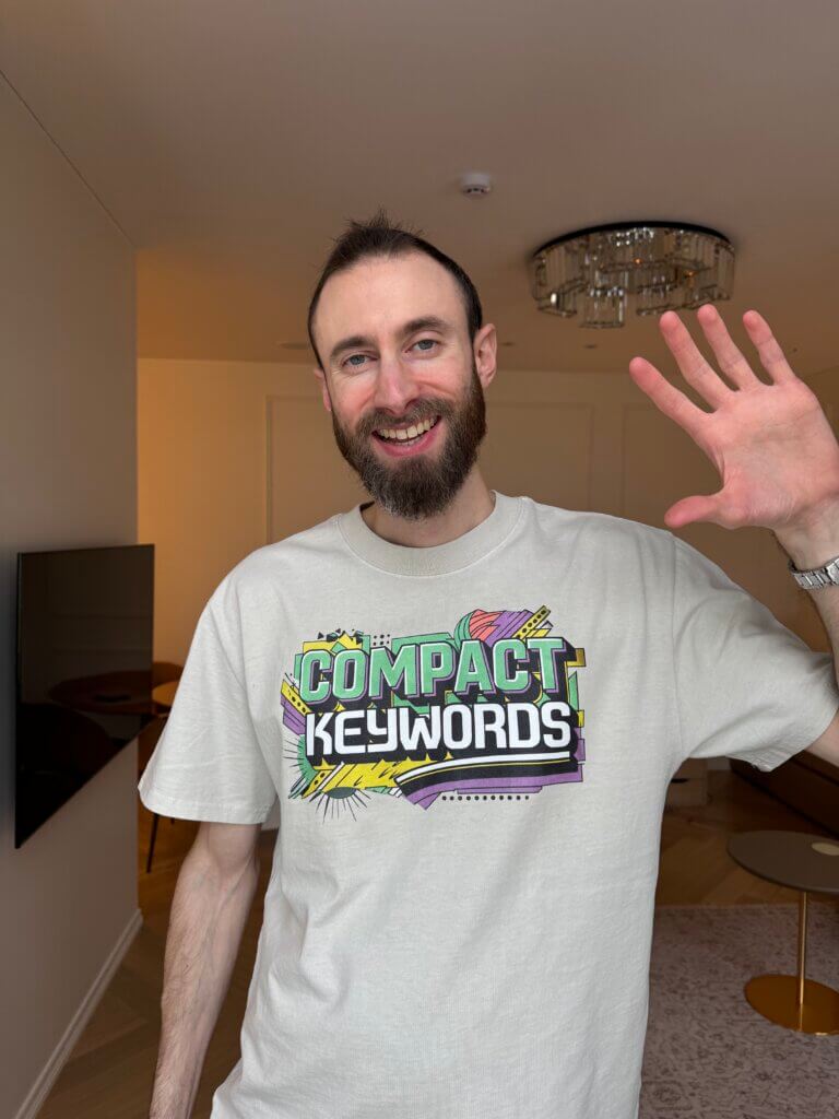 Edward Sturm upon the release of his SEO Program, Compact Keywords, in January 2025. Edward is smiling and waving while wearing a stylish Compact Keywords T-shirt.