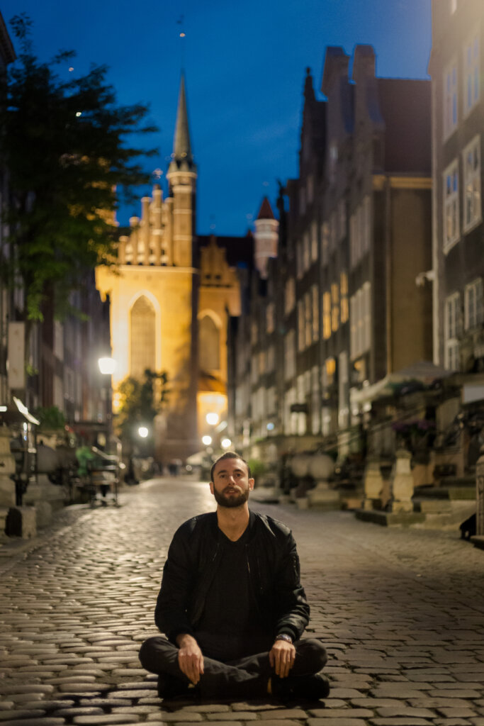 Edward Sturm sitting at night on the cobblestone streets of Gdańsk, Poland in 2019.