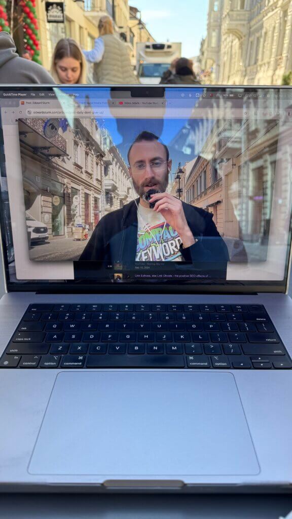 Edward Sturm, wearing a stylish Compact Keywords shirt, recording an episode of The Edward Show on a European street in Spring of 2025.