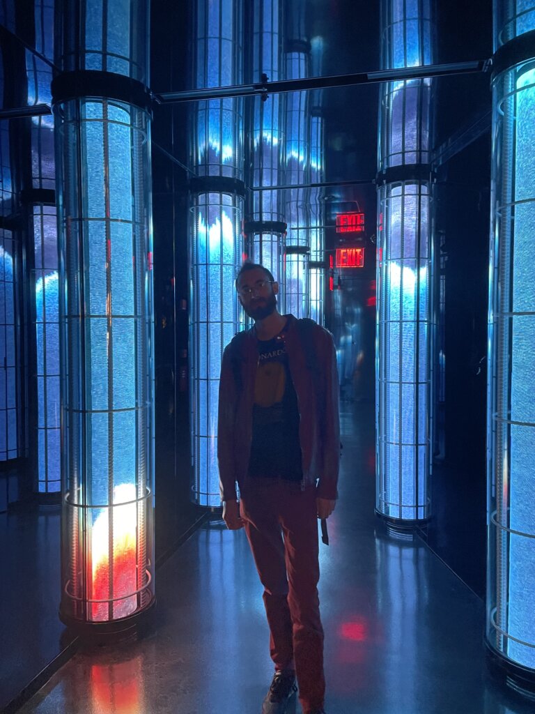 Edward Sturm in a red leather jacket with blue lighting in the lobby of The Edge in NYC. Photo taken in 2022.