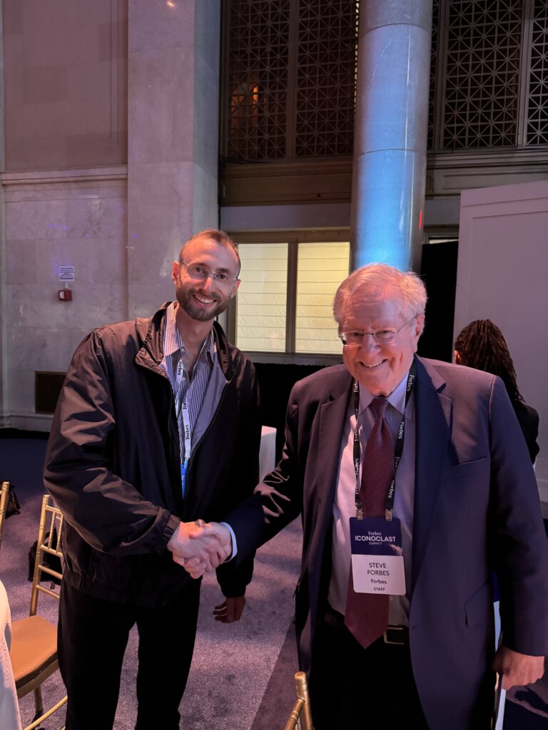 Edward Sturm shaking hands with Forbes Media Chairman and Editor-in-Chief, Steve Forbes. Photo at the Forbes Iconoclast Summit in 2024.