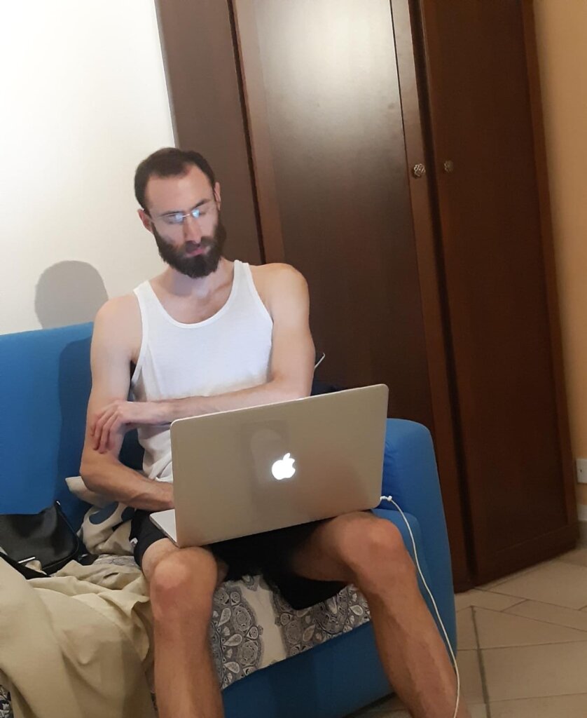 Edward Sturm in a tank top working on his laptop in Rome, Italy in 2022.