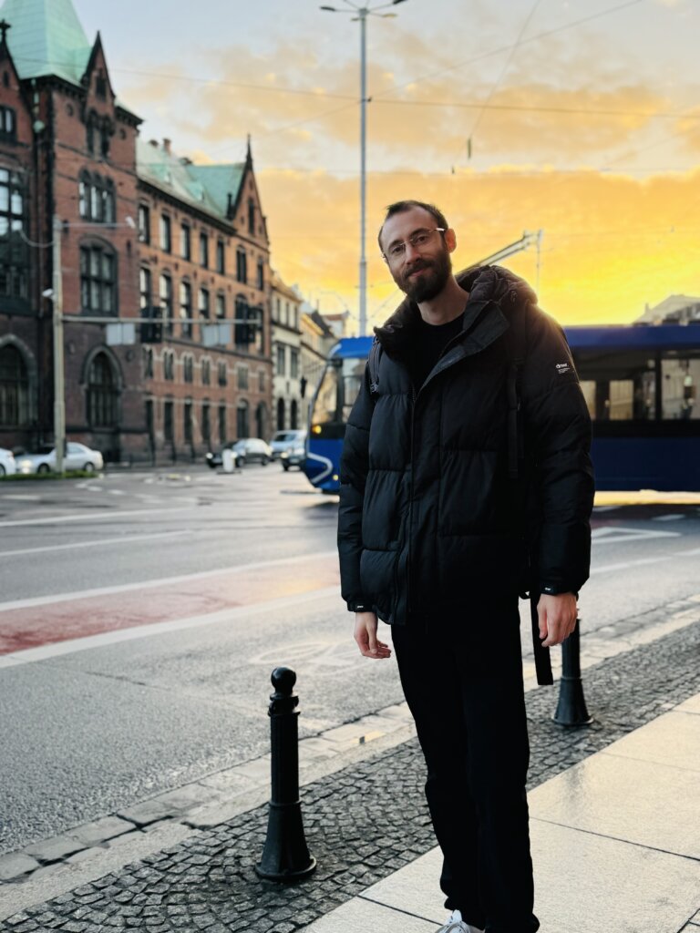 Edward Sturm on the streets of Wrocław, Poland during sunset with a tram behind him. Photo taken in 2023.